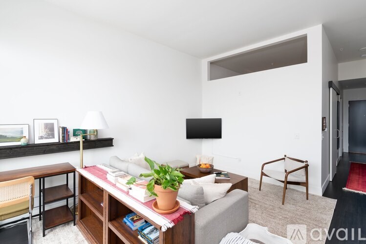 A living room with a grey couch, a wooden table, a TV, and a plant.
