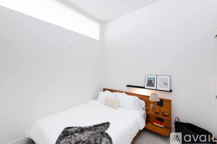 A bedroom with a bed, nightstand, and a picture on the wall.