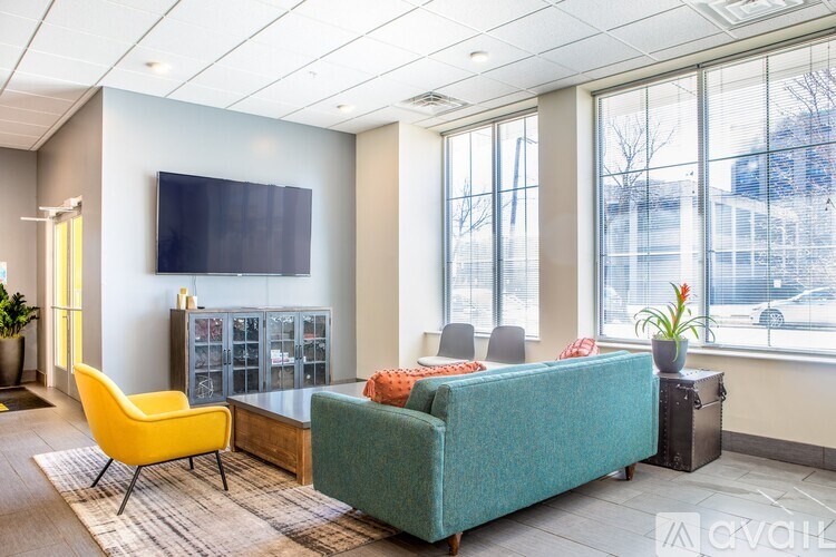 A living room with a yellow chair, a green couch, and a flat screen TV mounted on the wall.