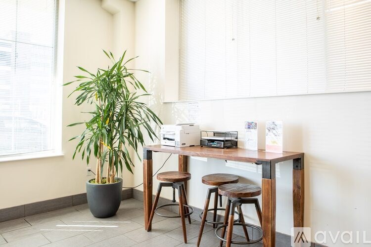 A room with a desk, chair, and a potted plant.