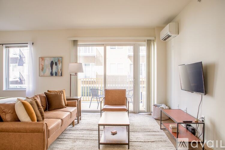 A living room with a brown couch, a coffee table, and a flat screen TV mounted on the wall.