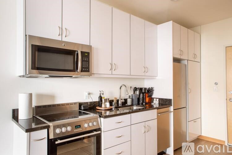 A kitchen with white cabinets and a black countertop.