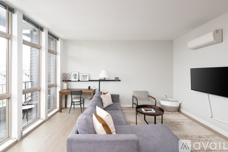 A living room with a grey couch, a black TV, and a wooden coffee table.
