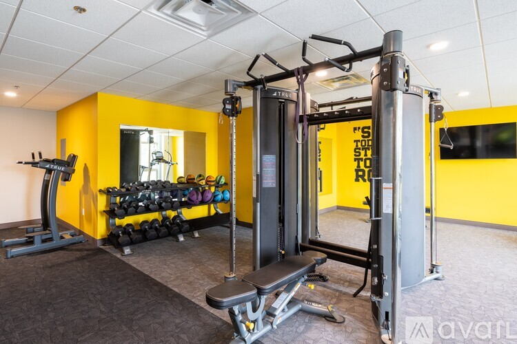 A gym with a yellow wall and a variety of equipment.