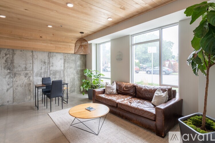 A living room with a brown leather couch, a wooden coffee table, and a large window.