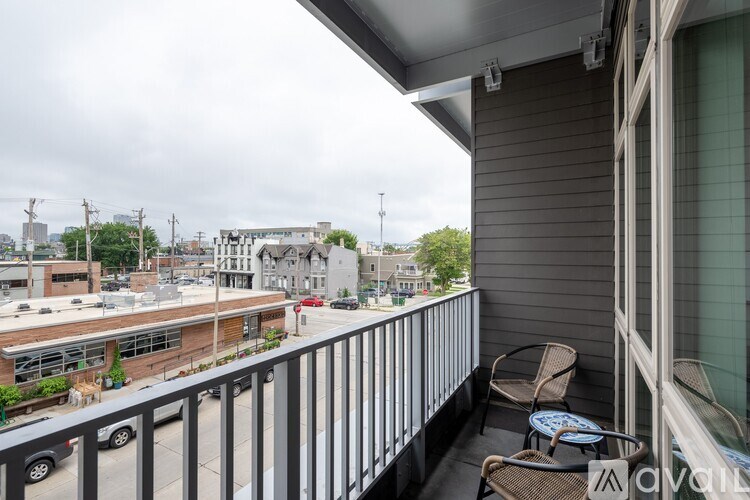 A balcony with a chair and table overlooking a street.
