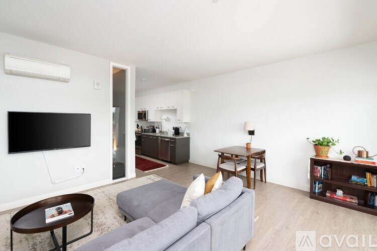 A living room with a grey couch and a television on the wall.