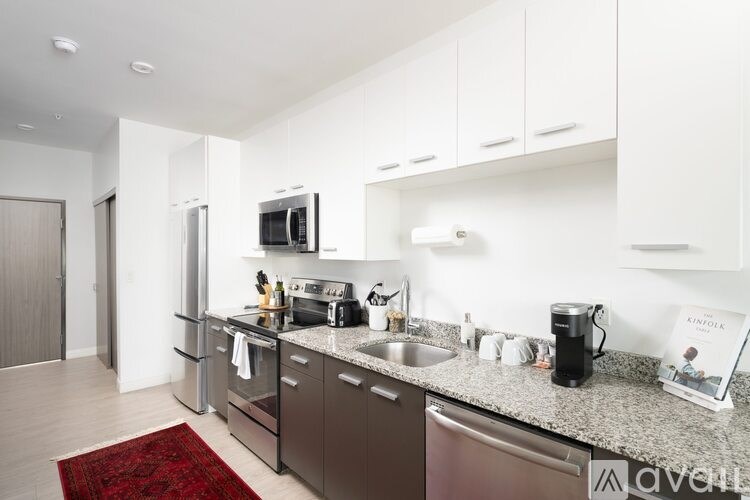 A kitchen with a red rug on the floor.
