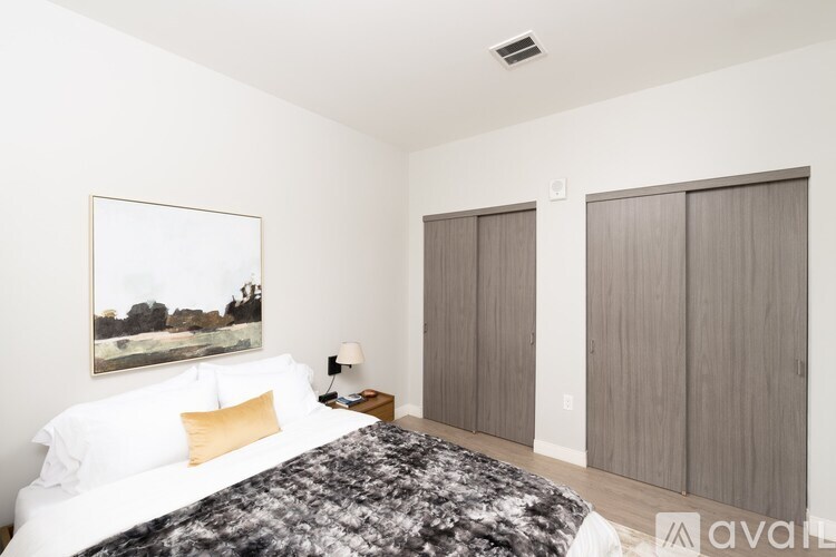 A bedroom with a large bed and a painting on the wall.