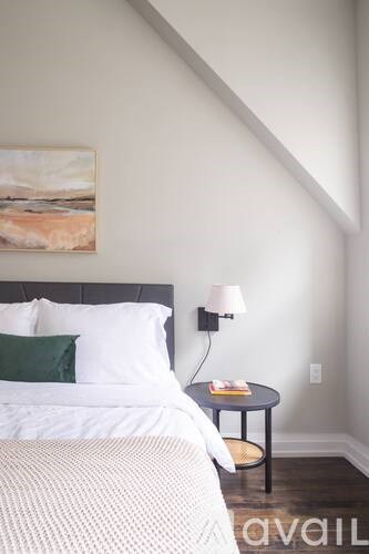 A bedroom with a bed, nightstand, and a painting on the wall.