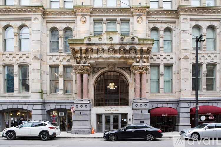 A black car is parked in front of a building with a large arched entrance.