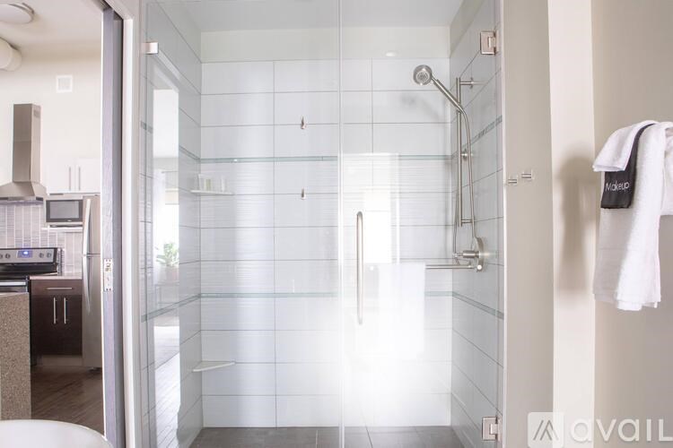 A bathroom with a glass shower stall and a towel hanging on the wall.