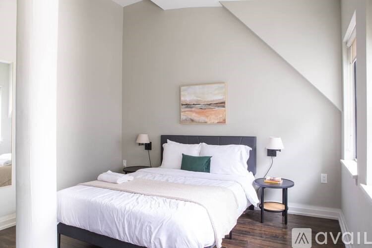 A bedroom with a large bed and a painting on the wall.