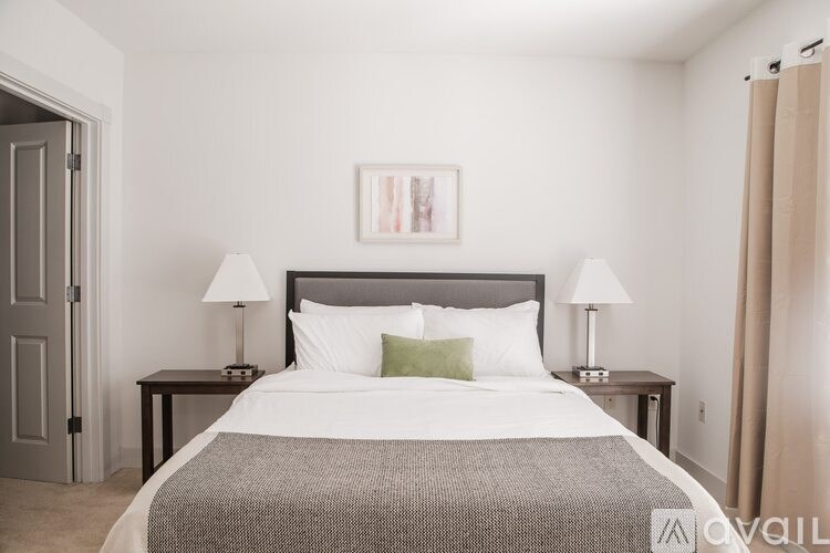 A bedroom with a large bed and two lamps on the side tables.