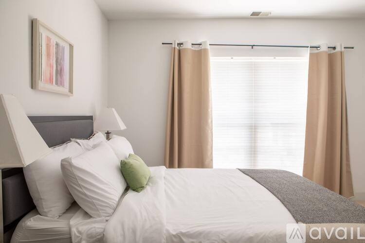 A bedroom with a bed, pillows, and a painting on the wall.