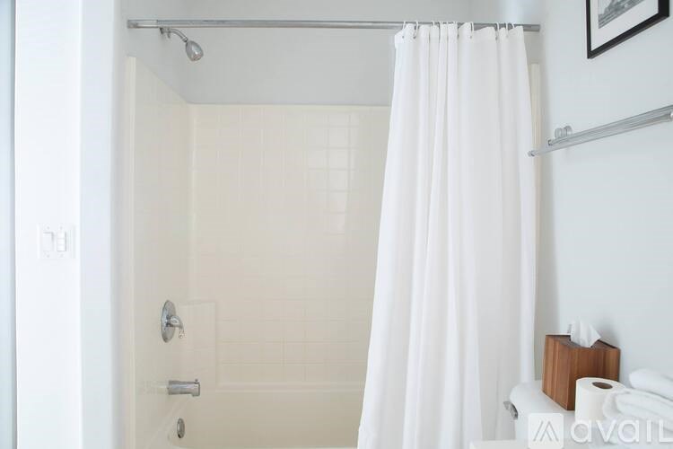 A white shower curtain hangs in a white bathroom.