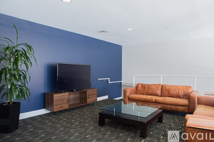 A living room with a brown couch, a black coffee table, and a flat screen TV.