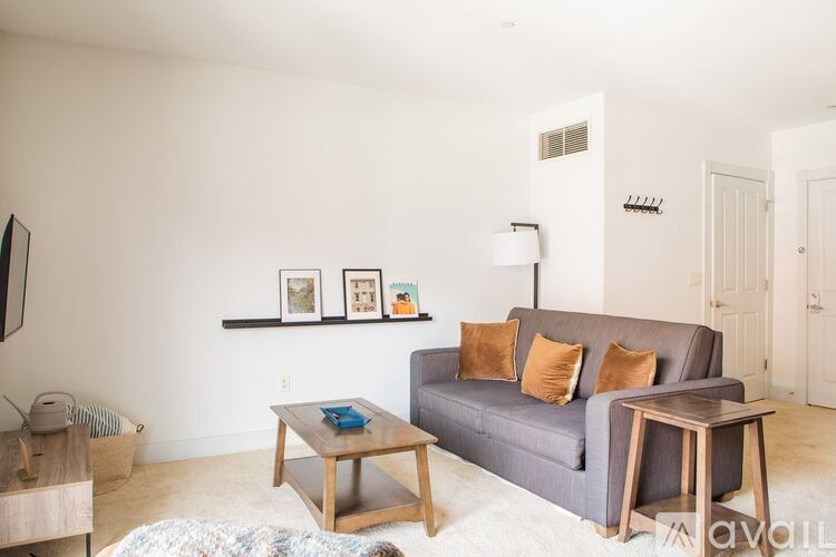 A living room with a grey couch, a coffee table, and a shelf with pictures on it.