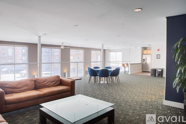 A spacious room with a glass table and chairs, a sofa, and a potted plant.