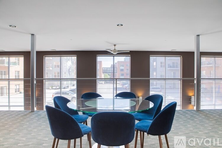 A conference room with blue chairs and a glass table.