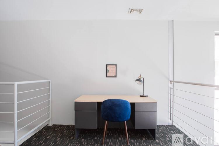 A small desk with a blue chair and a picture on the wall.