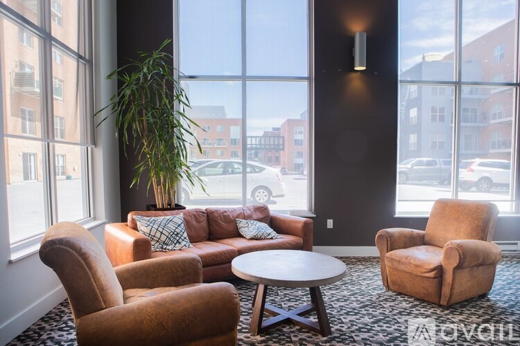 A living room with a couch, chairs, and a potted plant.