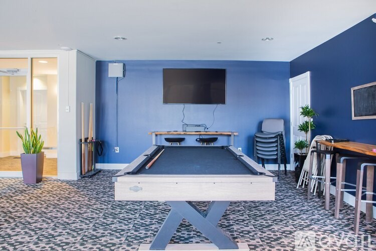 A room with a pool table and a television mounted on the wall.