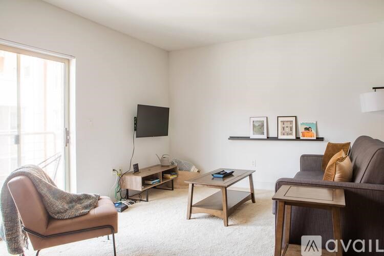 A living room with a grey couch, a chair, a coffee table, and a television.