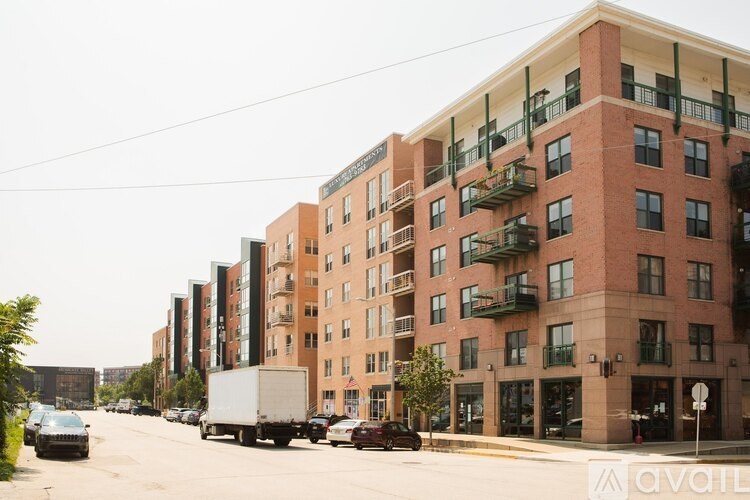 A street view of apartment buildings with cars parked on the side of the road.