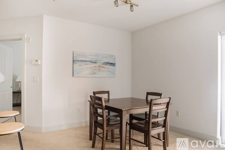 A dining room with a table and chairs and a painting on the wall.