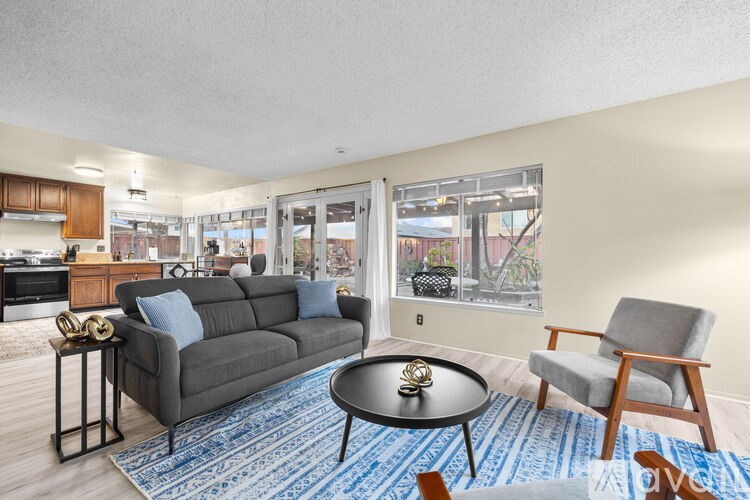 A living room with a grey couch, a black coffee table, and a blue rug.