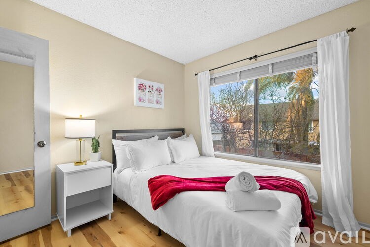 A bedroom with a bed, nightstand, and window.