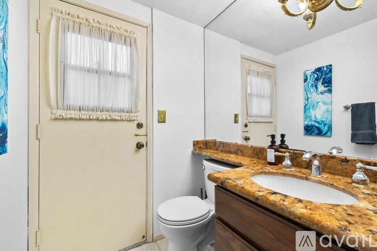A bathroom with a granite countertop and a white toilet.