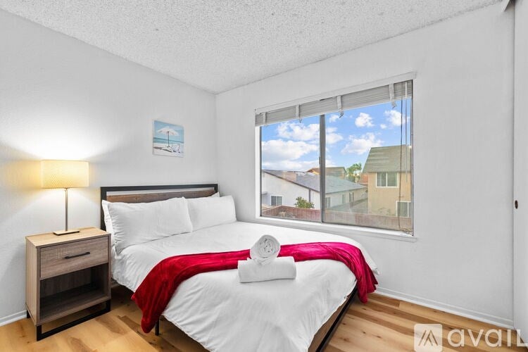A bedroom with a large bed and a window overlooking a cityscape.
