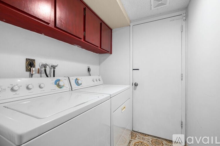 A white washing machine with a red cabinet above it.