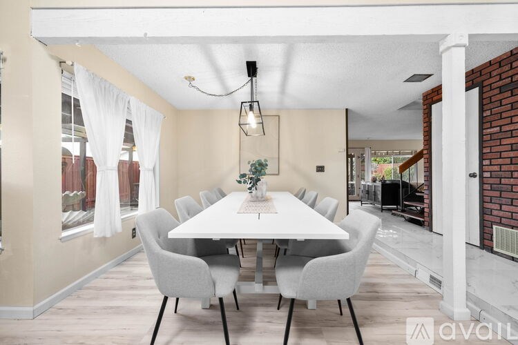 A dining room with a white table and grey chairs.
