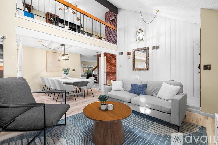 A living room with a grey couch, a coffee table, and a dining table set up.