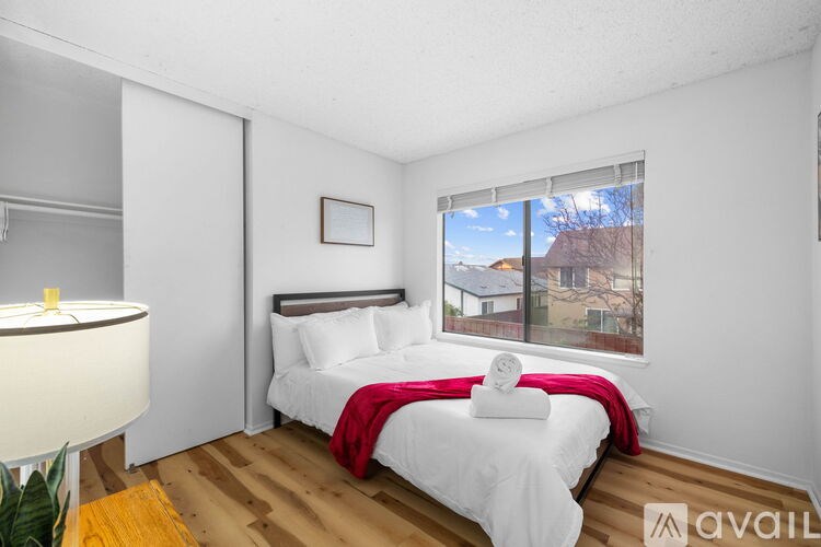 A bedroom with a large bed and a window overlooking a house.
