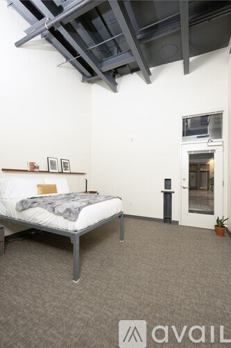 A bedroom with a bed, a small table, and a door.