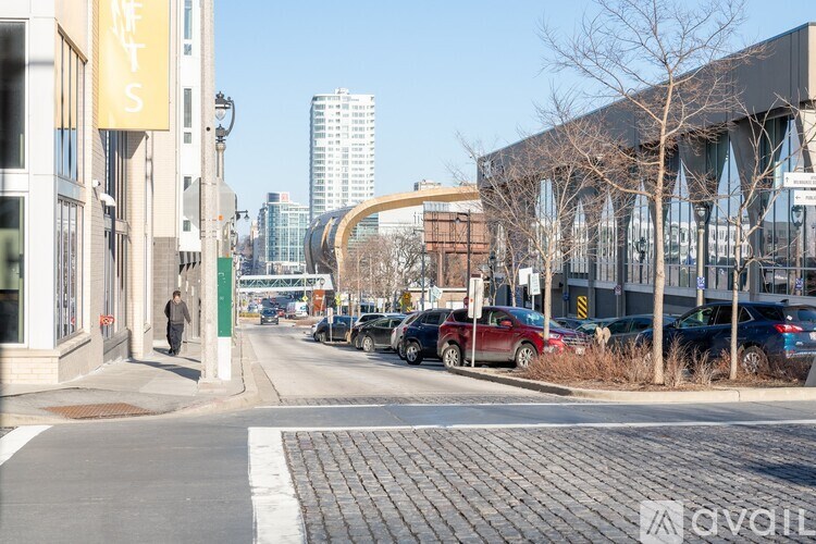 A city street with cars parked on the side and a pedestrian walking on the sidewalk.