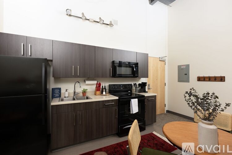 A kitchen with a black refrigerator and wooden cabinets.