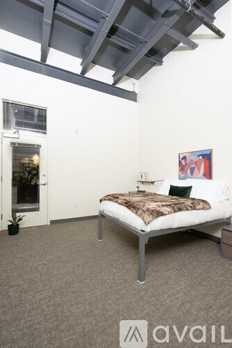 A bedroom with a bed, a small table, and a painting on the wall.