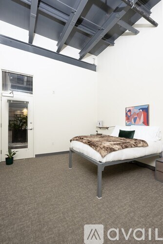 A bedroom with a bed, a small table, and a painting on the wall.