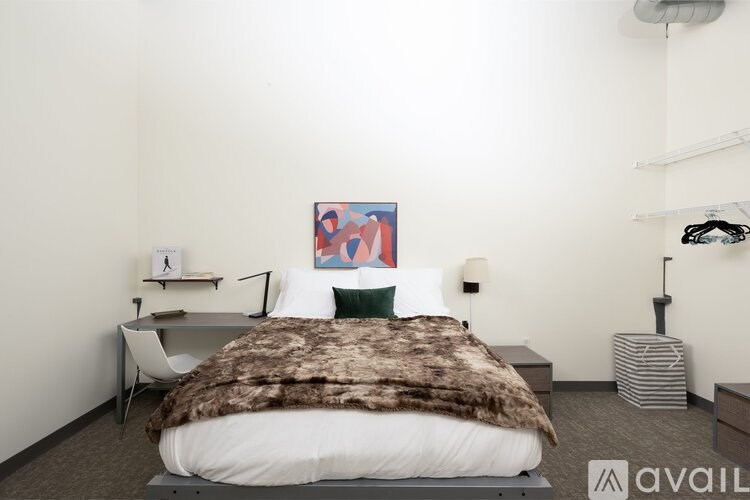 A bedroom with a bed, a chair, a desk, and a painting on the wall.