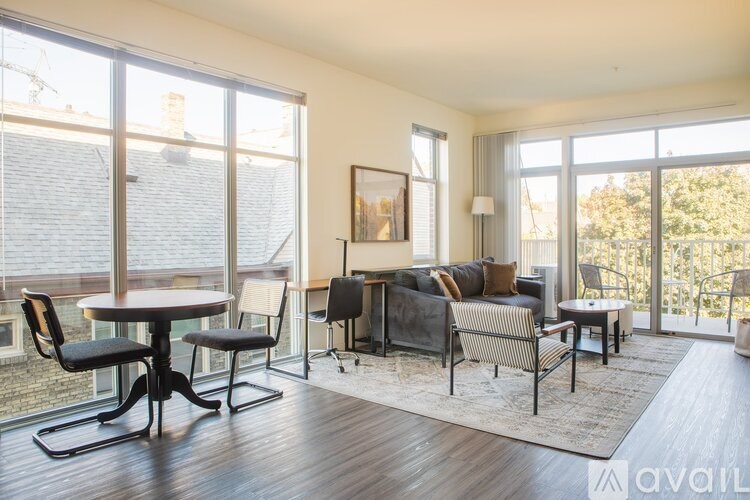 A living room with a table and chairs in front of a large window.