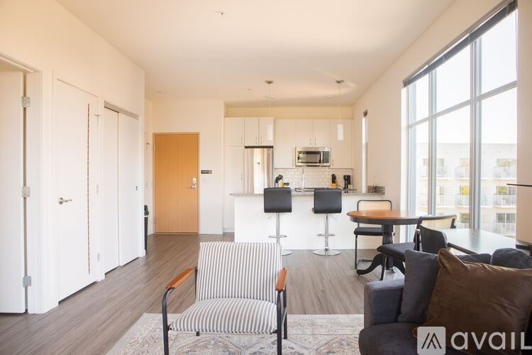 A living room with a striped couch and a kitchen area in the background.