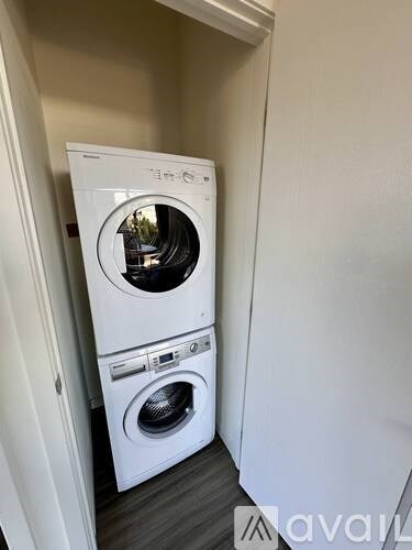 A white washing machine and dryer in a small, narrow laundry room.
