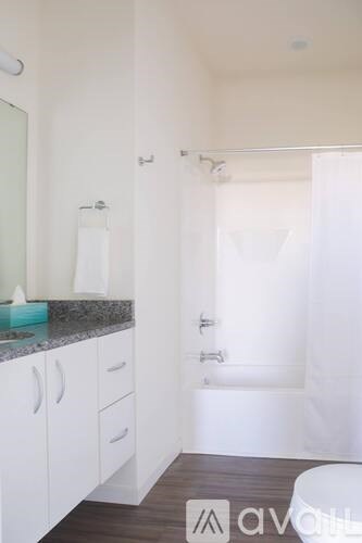 A white bathroom with a marble countertop and a walk-in shower.