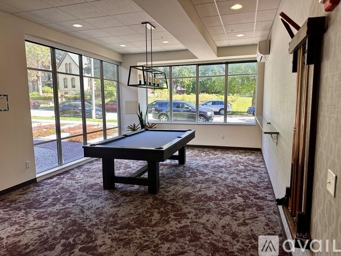 A room with a pool table and a view of the street outside.