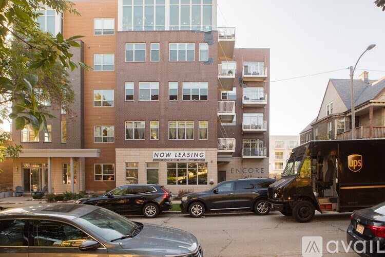 A UPS truck is parked in front of a building with a sign that says "NOW LEASING".